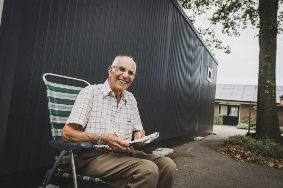 Bewoner zit bij tijdelijke mantelzorgwoning krant te lezen