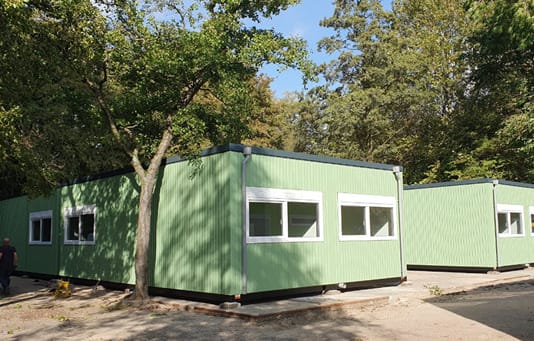 Groene wisselwoningen op maat gemaakt dichtbij appartementen tijdens renovatieproject.