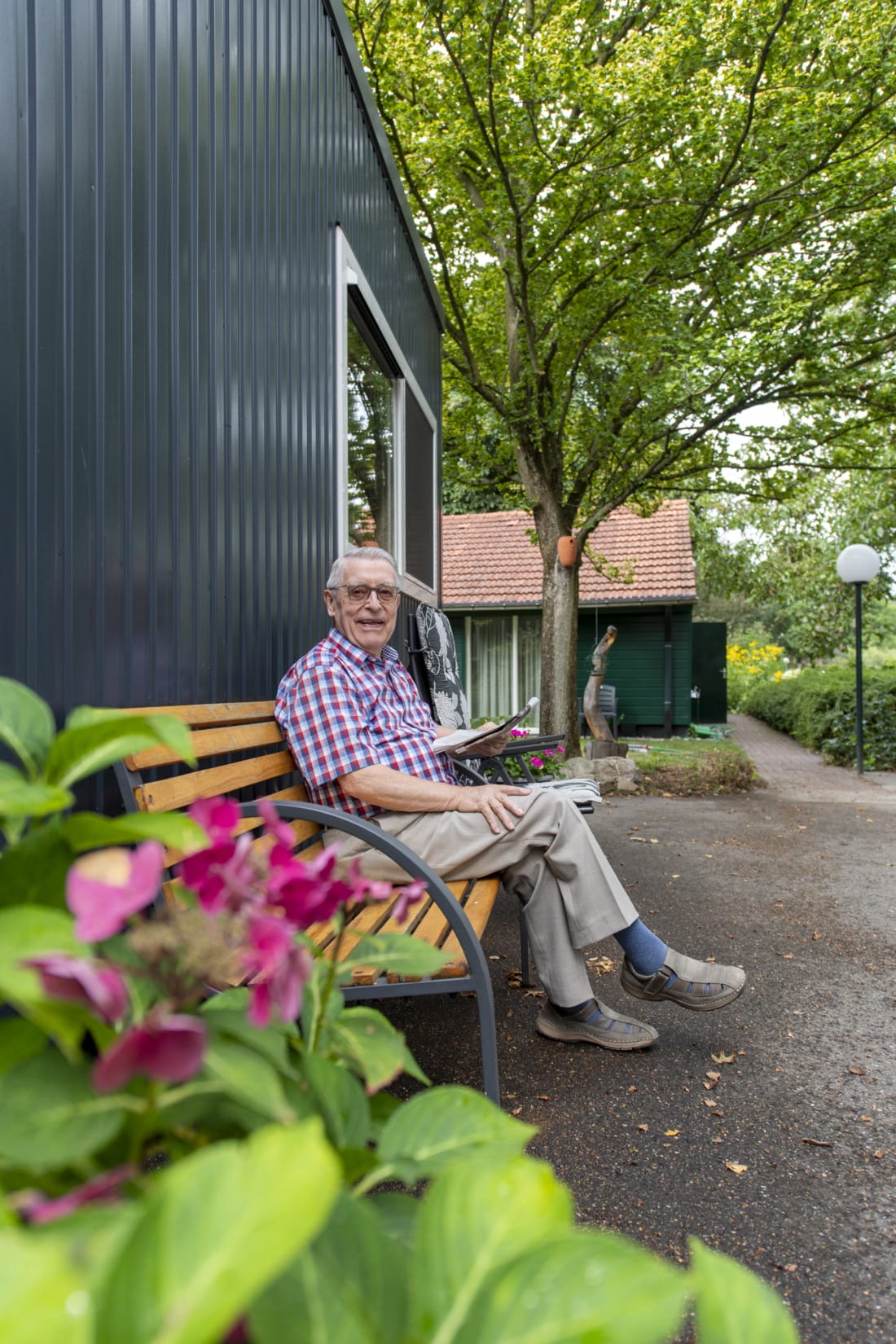 Bewoner zit bij zijn tijdelijke mantelzorgwoning krant te lezen