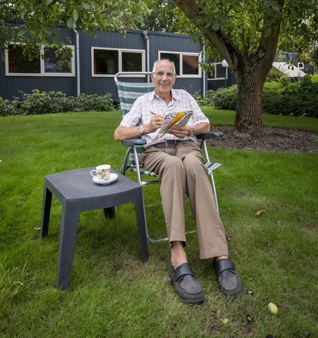 Bewoner zit voor tijdelijke mantelzorgwoning thee te drinken